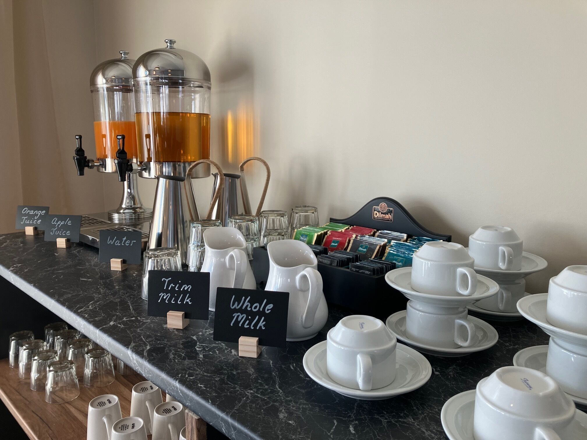 A coffee station with a coffee machine, milk dispensers, and a variety of coffee pods.
