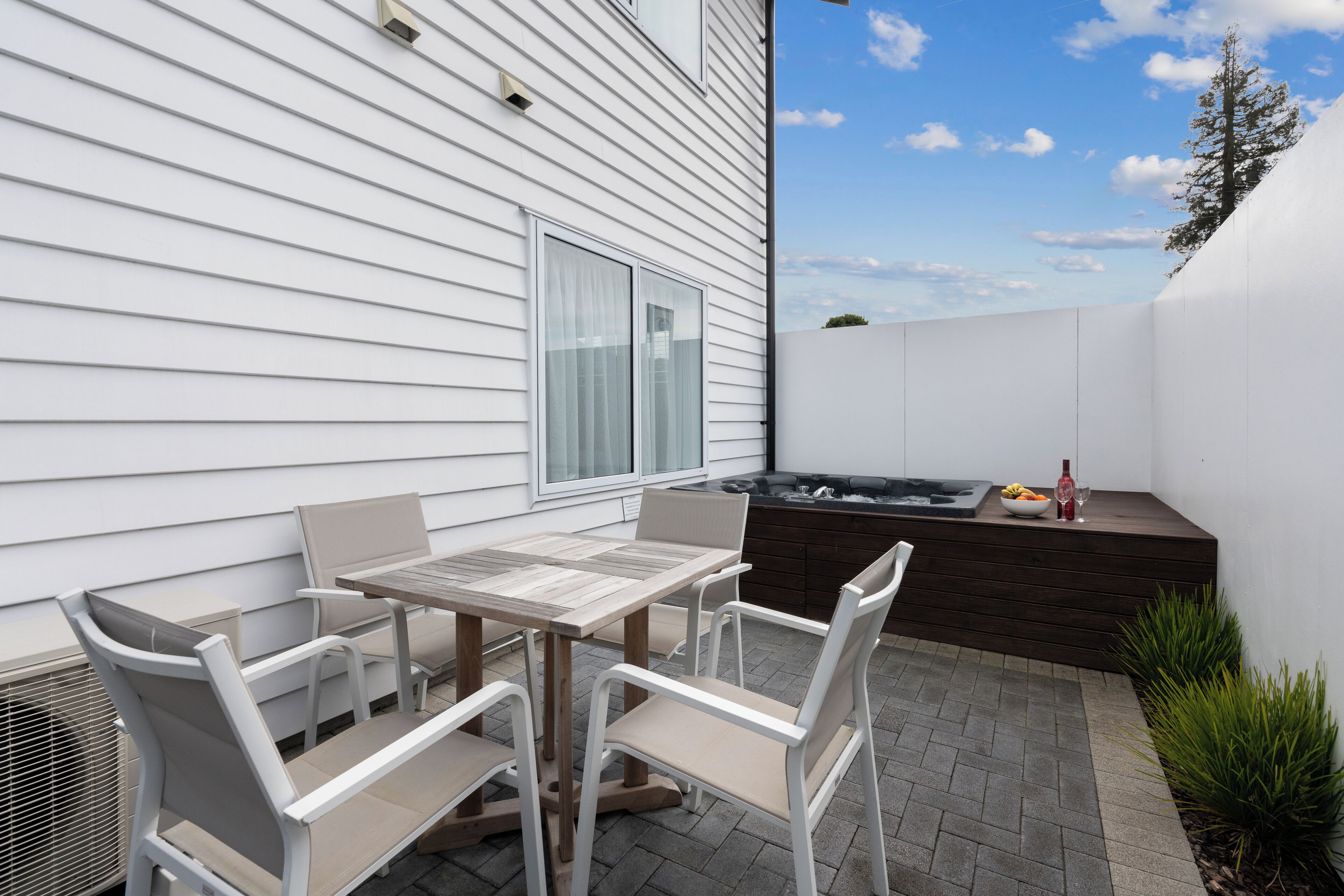 An outdoor patio with a table and chairs, a hot tub, and a small garden area.