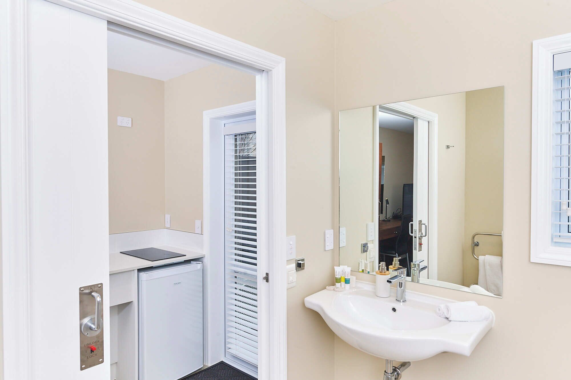 A bathroom with a white sink, mirror, and a door leading to a closet.