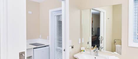 Un baño con lavamanos blanco, espejo y una puerta que da a un armario.