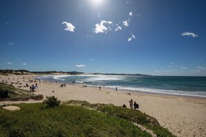 A beach with people, a clear sky, and the ocean.