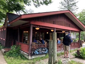 A rustic red building with a porch, labeled "Ida Red's Cottage," where people are seated at tables. - Celestial Pointe Condominium 1 Bedroom 1 Bathroom, Sleeps 4 @ Northern Lights (Douglas)