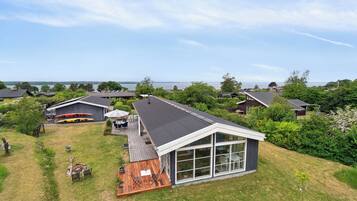 Een modern huis met een groot raam, een terras en uitzicht op het water.