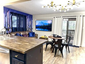 Une cuisine moderne dotée d’un plan de travail en bois, d’un évier encastré et d’un coin repas avec une table ronde et des chaises.