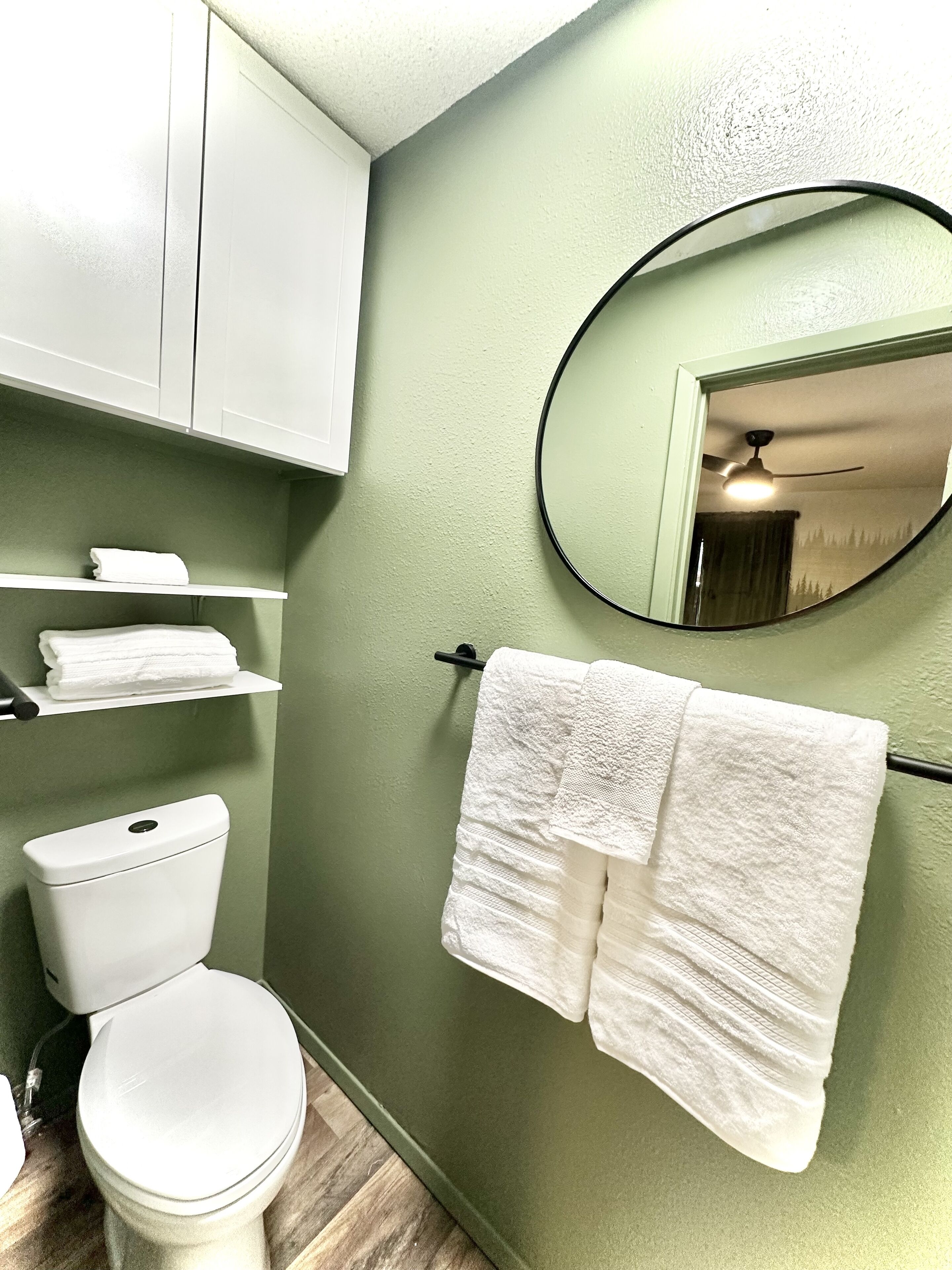 Un bany amb vàter, un lavabo blanc, un mirall i dues tovalloles penjades d'un suport.