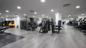 Une salle de sport moderne équipée de divers appareils d’exercice, notamment des machines de musculation et des tapis de course.