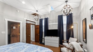 A bedroom with a large bed, a TV, a chair, and a ceiling light. - Springside Bourbon Getaway (Georgetown)
