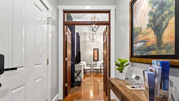 A hallway with a wooden reception desk, framed artwork, and a rug. - Springside Bourbon Getaway (Georgetown)