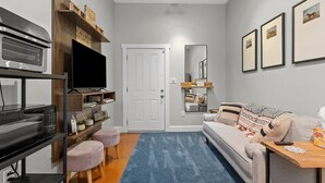 A living room with a sofa, a coffee table, a TV, and a bookshelf. - Springside Bourbon Getaway (Georgetown)