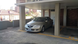 Un'auto parcheggiata in un'area di parcheggio coperta, con pavimento in cemento e una linea gialla di delimitazione.