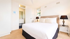 Una camera d'albergo con un letto grande, lampade ai comodini, un tavolino e vista sull'esterno.