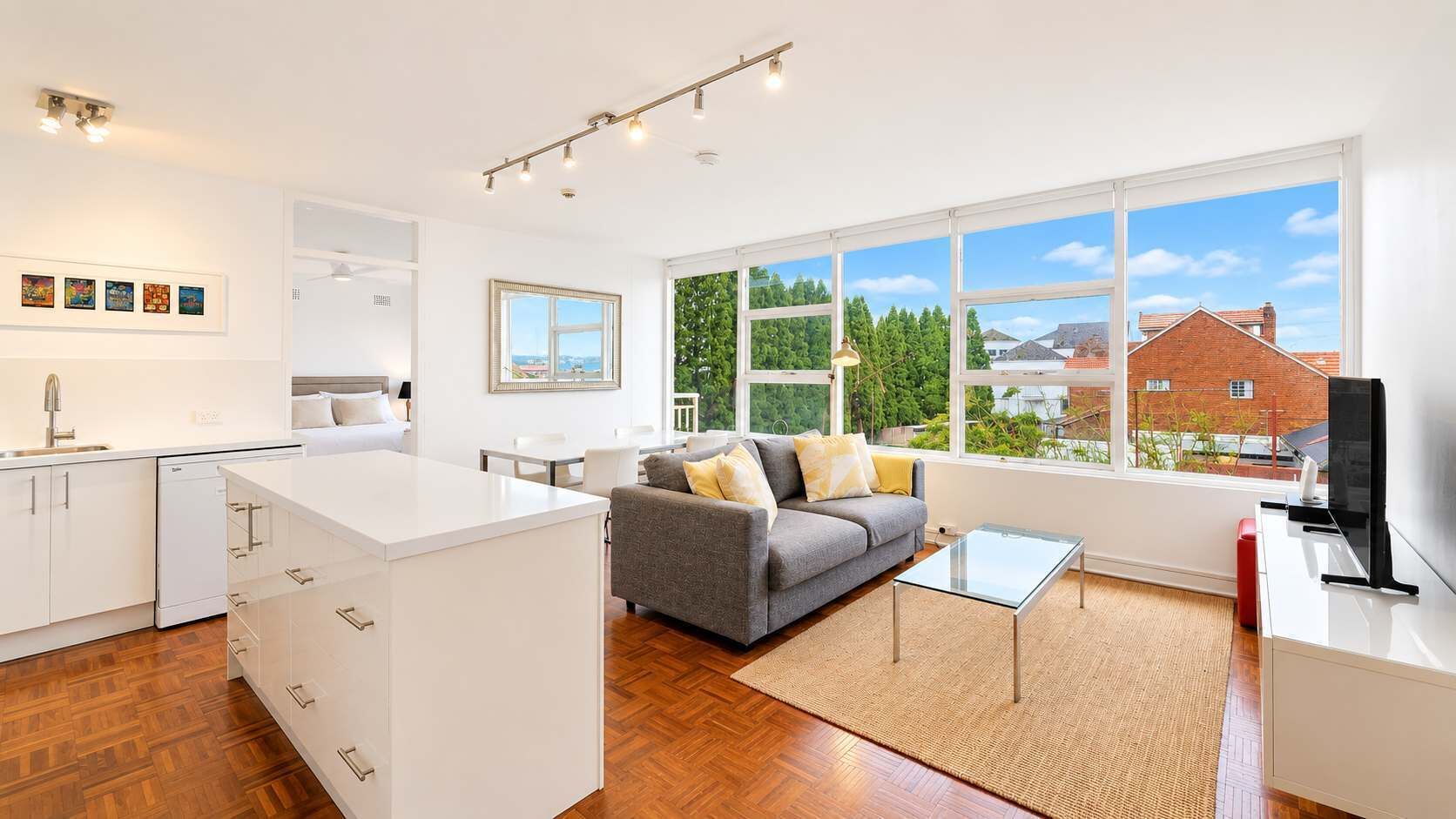 A modern apartment with a kitchen, dining area, and living room with a large window.