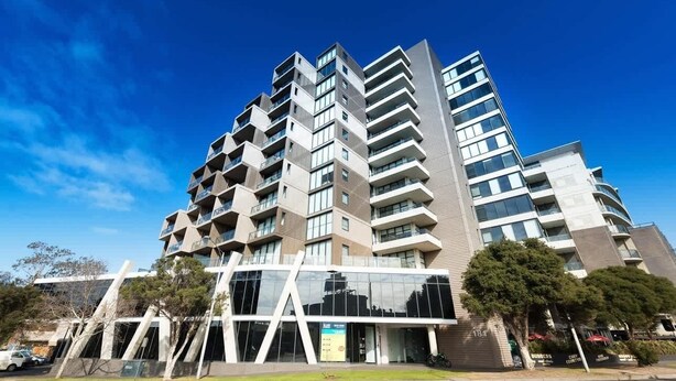 Un edificio moderno de varios pisos con balcones, ventanas amplias y cielo despejado.