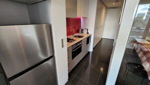 Una cocina moderna con electrodomésticos de acero inoxidable, un salpicadero rojo y vistas al área de estar exterior.