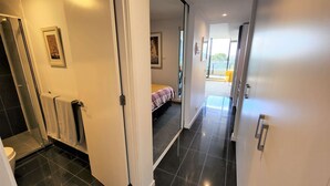 Una habitación de hotel moderna con baño, una cama con colcha a cuadros y vistas al exterior.