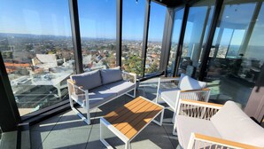 A high-rise balcony with a sofa, chairs, and a wooden table.