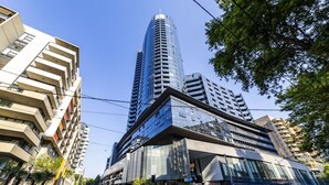 A modern urban street with high-rise buildings, including a prominent curved skyscraper.
