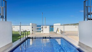 Une piscine offrant une vue dégagée sur les environs, notamment une clôture blanche et un bâtiment situé au loin.