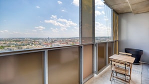 A balcony with a city view, a table, and a trash bin. - Fresh Landstraße 1BR w/ Pool, Gym & Cellar, nr Hyblerpark, by Blueground (Vienna)