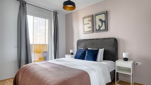 A modern bedroom with a large bed, grey curtains, a grey headboard, two bedside tables with lamps, and abstract art on the wall. - Fresh Landstraße 1BR w/ Pool, Gym & Cellar, nr Hyblerpark, by Blueground (Vienna)