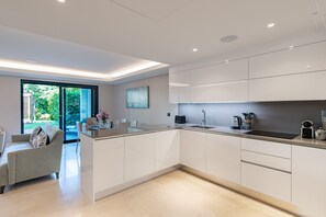 A modern kitchen with white cabinetry, a built-in island, and a large window offering a view of the outdoors.