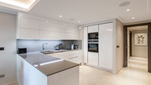 Una cocina moderna con armarios blancos, una isla central y electrodomésticos integrados.