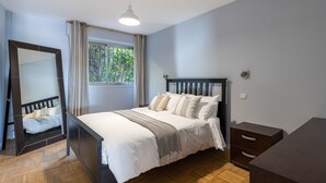 A bedroom with a bed, a dresser, a mirror, and a window with curtains. - Flora Sur Mer 2 bedroom apartment (Villefranche-sur-Mer)