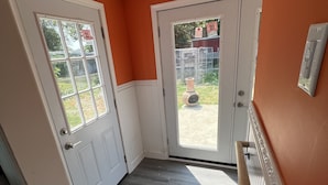 Ein Zimmer mit orangefarbenen Wänden, Holzboden und einer weißen Tür mit Fenster.