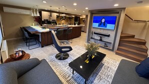 Ein modernes Wohnzimmer mit einer Couch, einem Couchtisch und einem Fernseher, der einen Nachrichtensender zeigt.