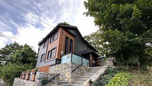 Ein zweistöckiges Haus mit einer Steinstufen-Eingangstreppe, umgeben von üppigem Grün.