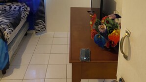 A room with a bed, a desk with a phone, a wall-mounted TV, and an air conditioner. - Family Reunions Holiday 4 Bedrooms, 5 Beds Rentals in St Thomas,jamaica (Port Morant)