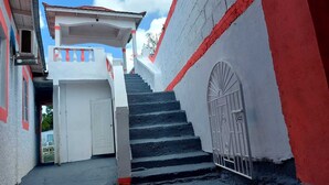 A narrow street with a staircase leading to a building with a white door and a metal gate. - Family Reunions Holiday 4 Bedrooms, 5 Beds Rentals in St Thomas,jamaica (Port Morant)