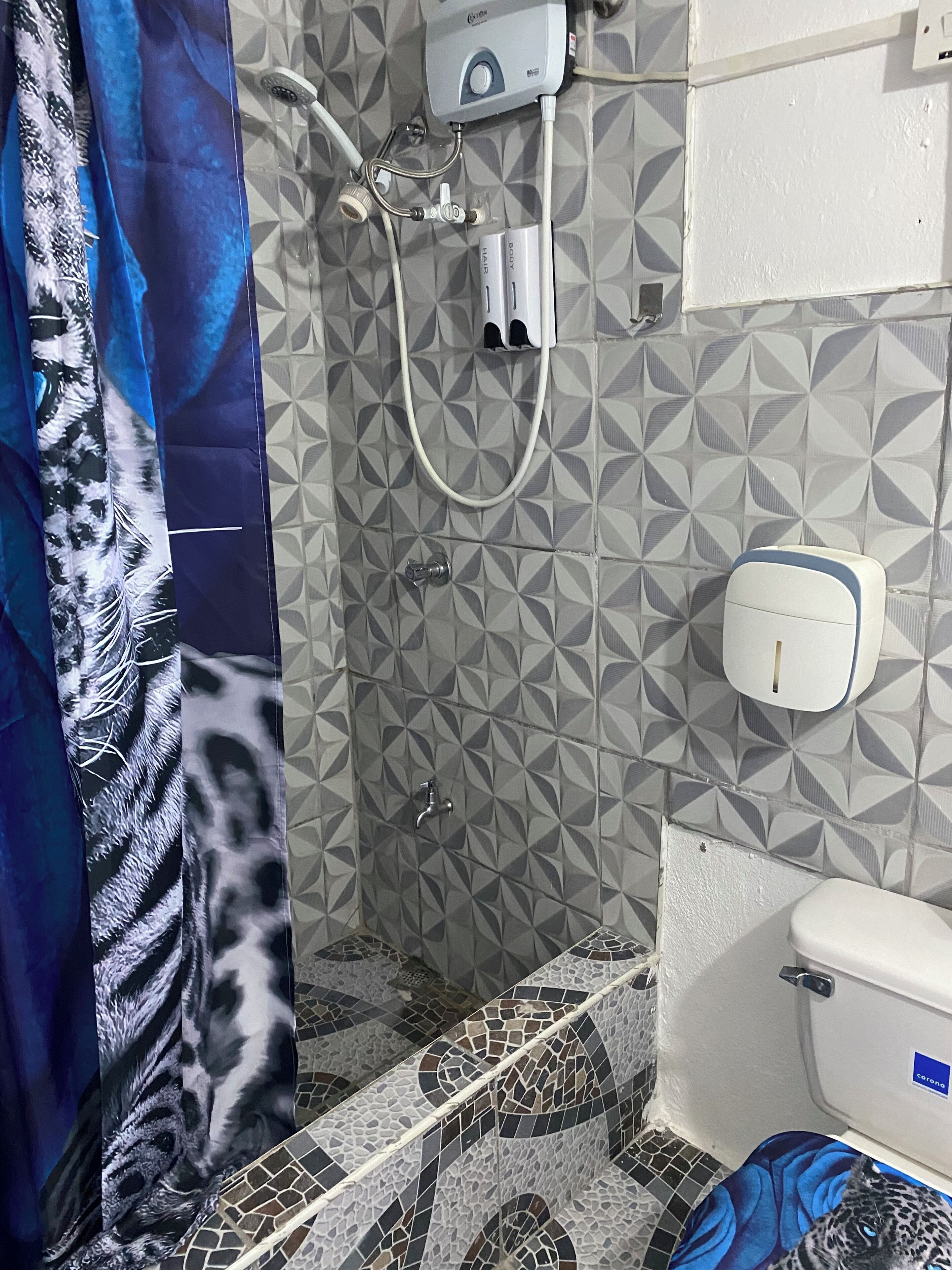 Une salle de bain avec des carreaux décorés, une douche, des toilettes et un sèche-mains.