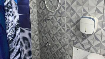 Une salle de bain avec des carreaux décorés, une douche, des toilettes et un sèche-mains.