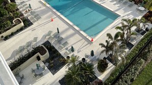 A resort with a swimming pool, lounge chairs, and palm trees. - Wake up to the sound of waves and panoramic Gulf views at this beachfront condo  (Marco Island)