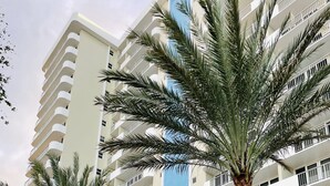 A multi-story hotel with balconies, palm trees, and a blue accent wall. - Wake up to the sound of waves and panoramic Gulf views at this beachfront condo  (Marco Island)