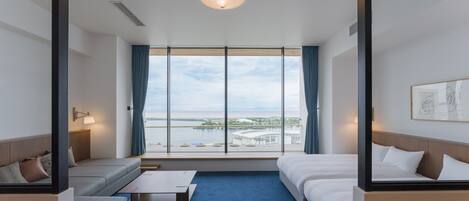 Habitación de hotel con un ventanal grande, una cama, un sofá y una mesita.