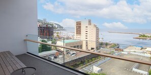 A balcony with a view of a marina, a hotel, and a coastal cityscape.