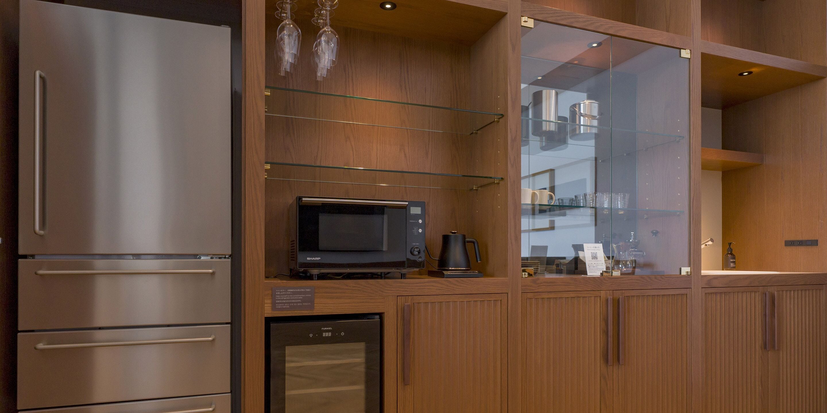 A modern kitchen with stainless steel appliances, wooden cabinetry, and a glass-fronted microwave.