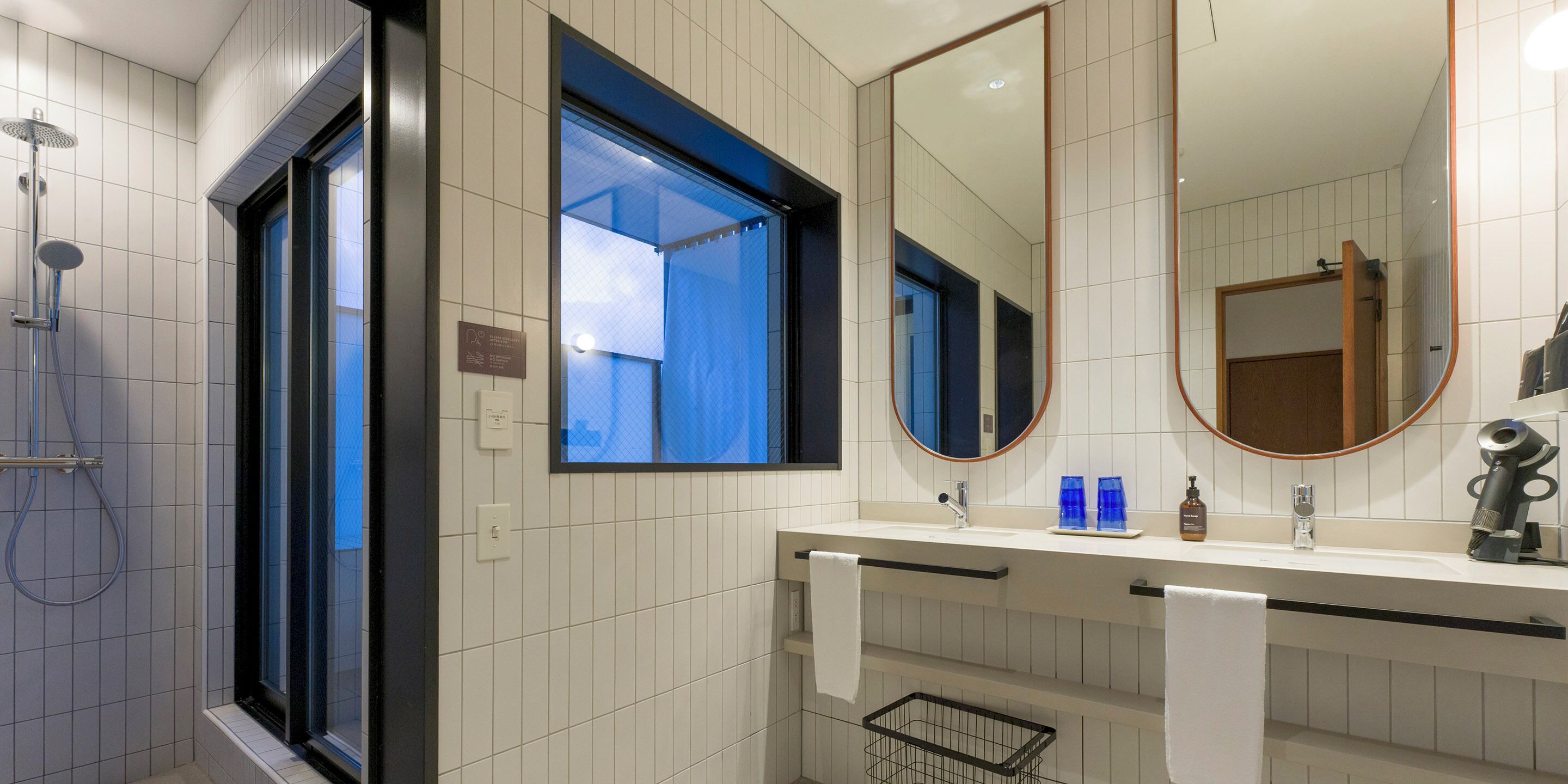 A modern bathroom with a shower, a sink with a mirror, and a window.