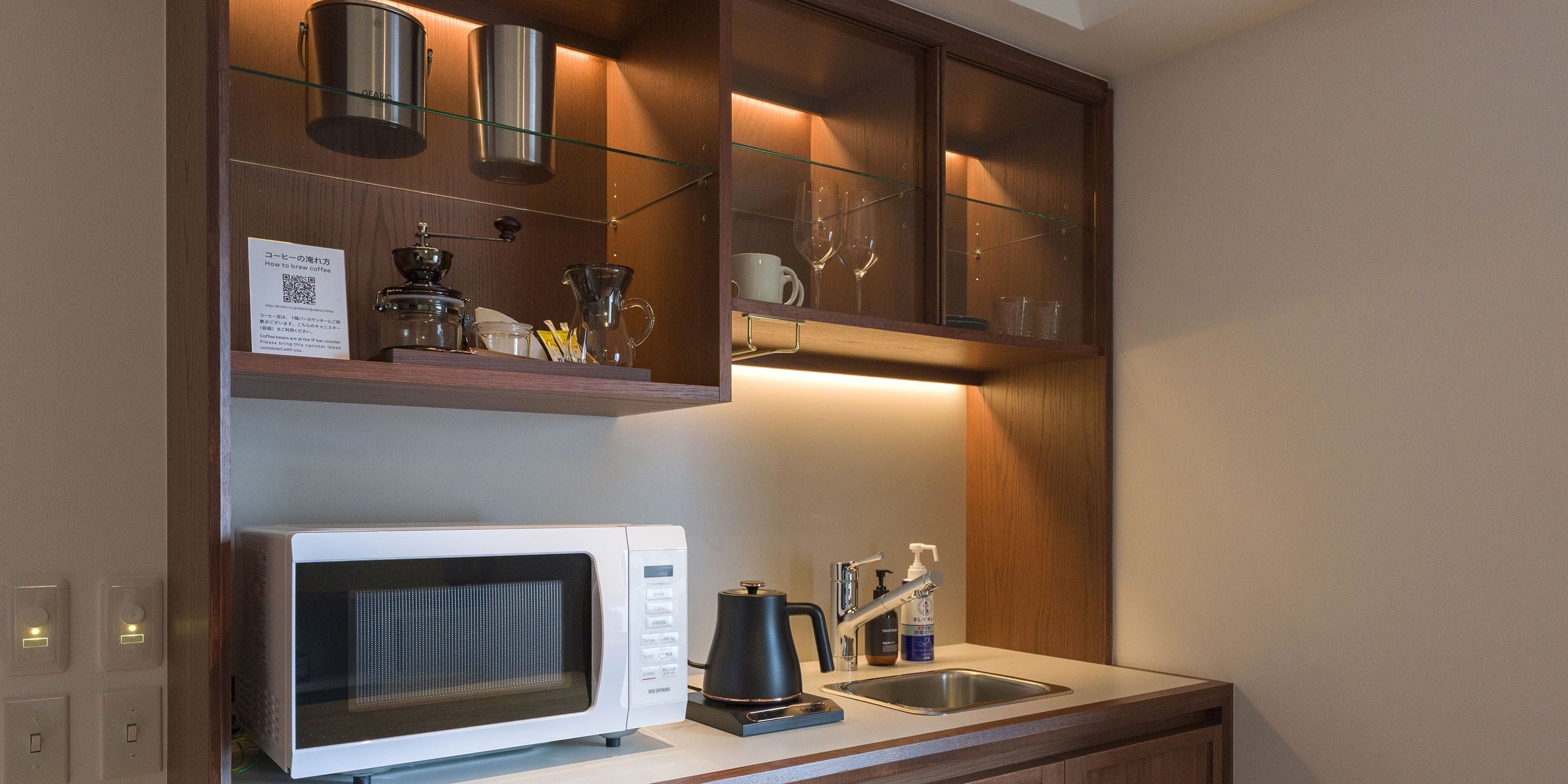 A compact kitchen with a microwave, coffee maker, and a sink.
