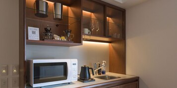 A compact kitchen with a microwave, coffee maker, and a sink.