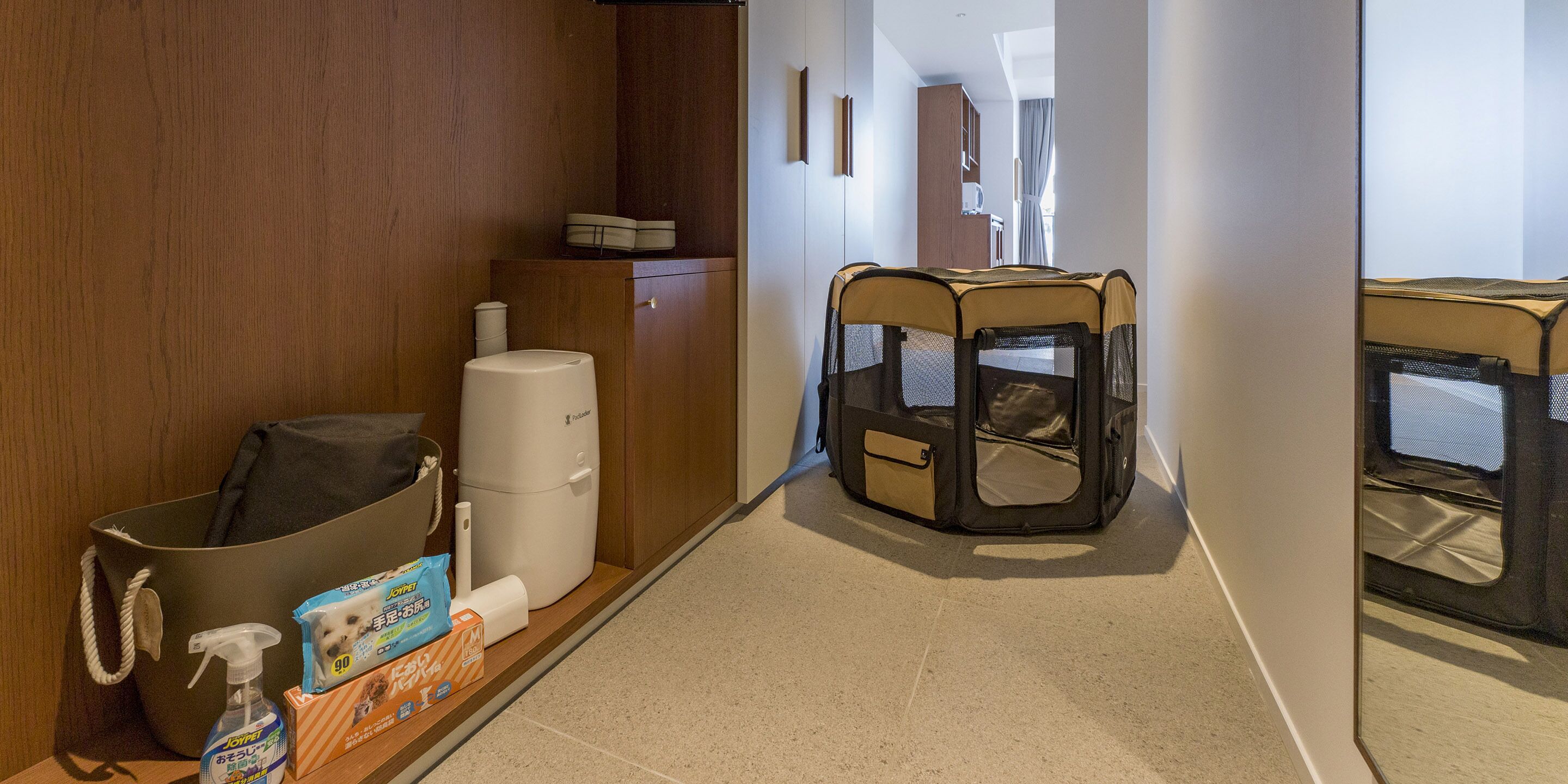 A hallway with a pet playpen, a trash bin, a wastebasket, and a cleaning product.