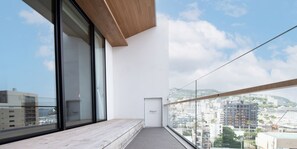 A modern balcony with a view of a cityscape, a wooden floor, and a door leading to an interior space.