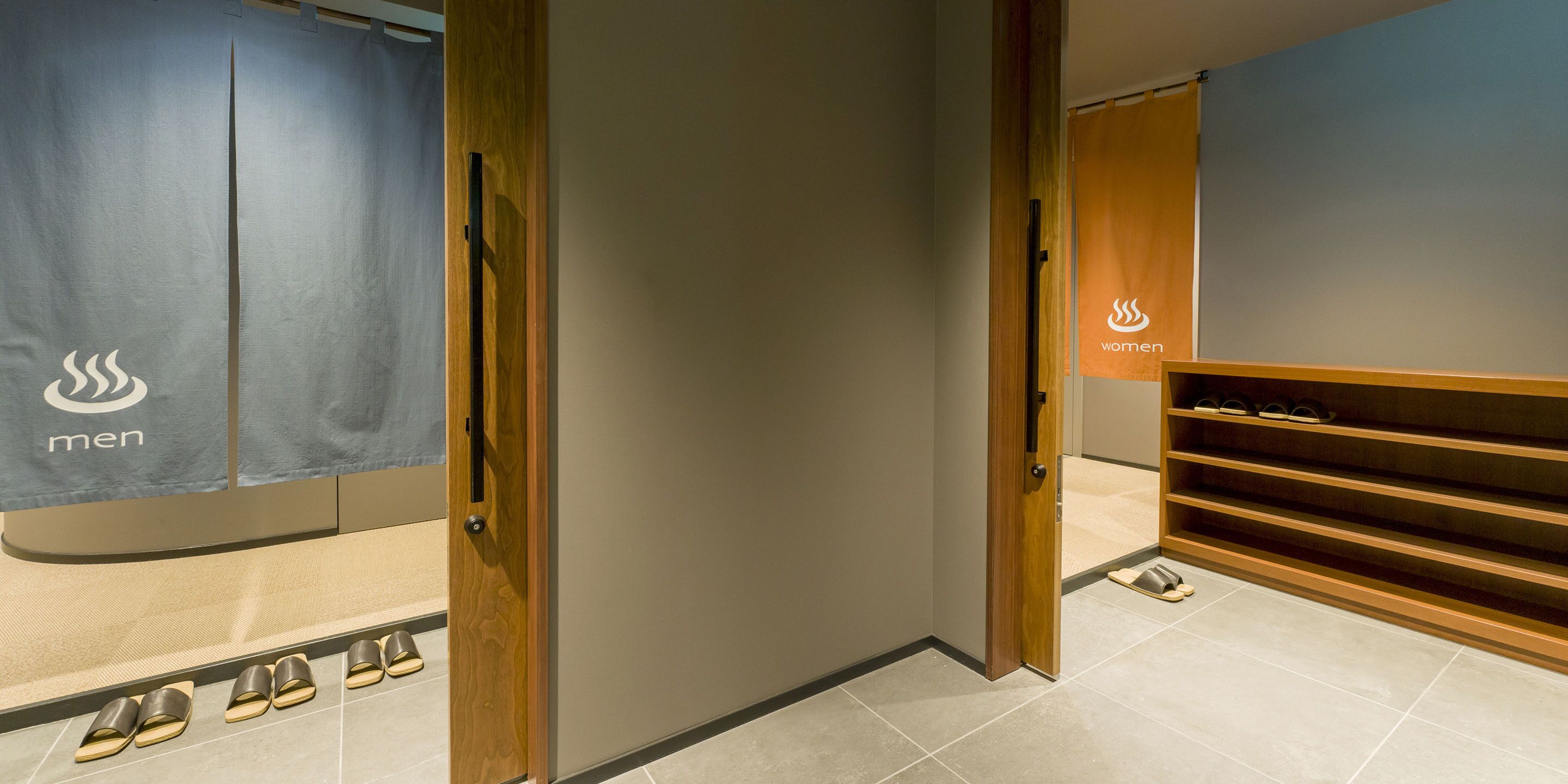 A men's and women's changing room with wooden shelves and a tiled floor.