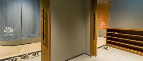 A men's and women's changing room with wooden shelves and a tiled floor.