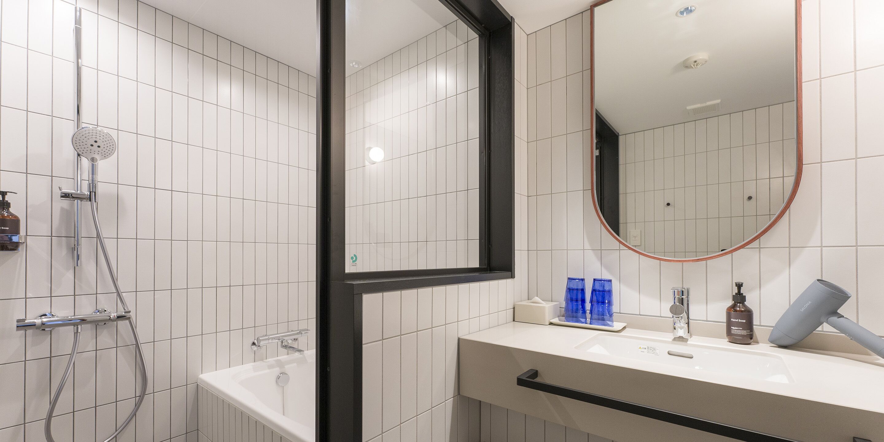 A modern bathroom with a bathtub, a shower, a sink with a mirror, and toiletries.