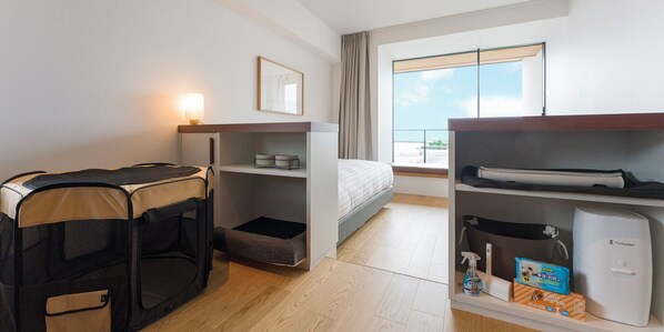 A hotel room with a bed, a desk with a computer, a pet carrier, a shelf with cleaning supplies, and a window with a view. - Rakuten STAY Atami (Atami)