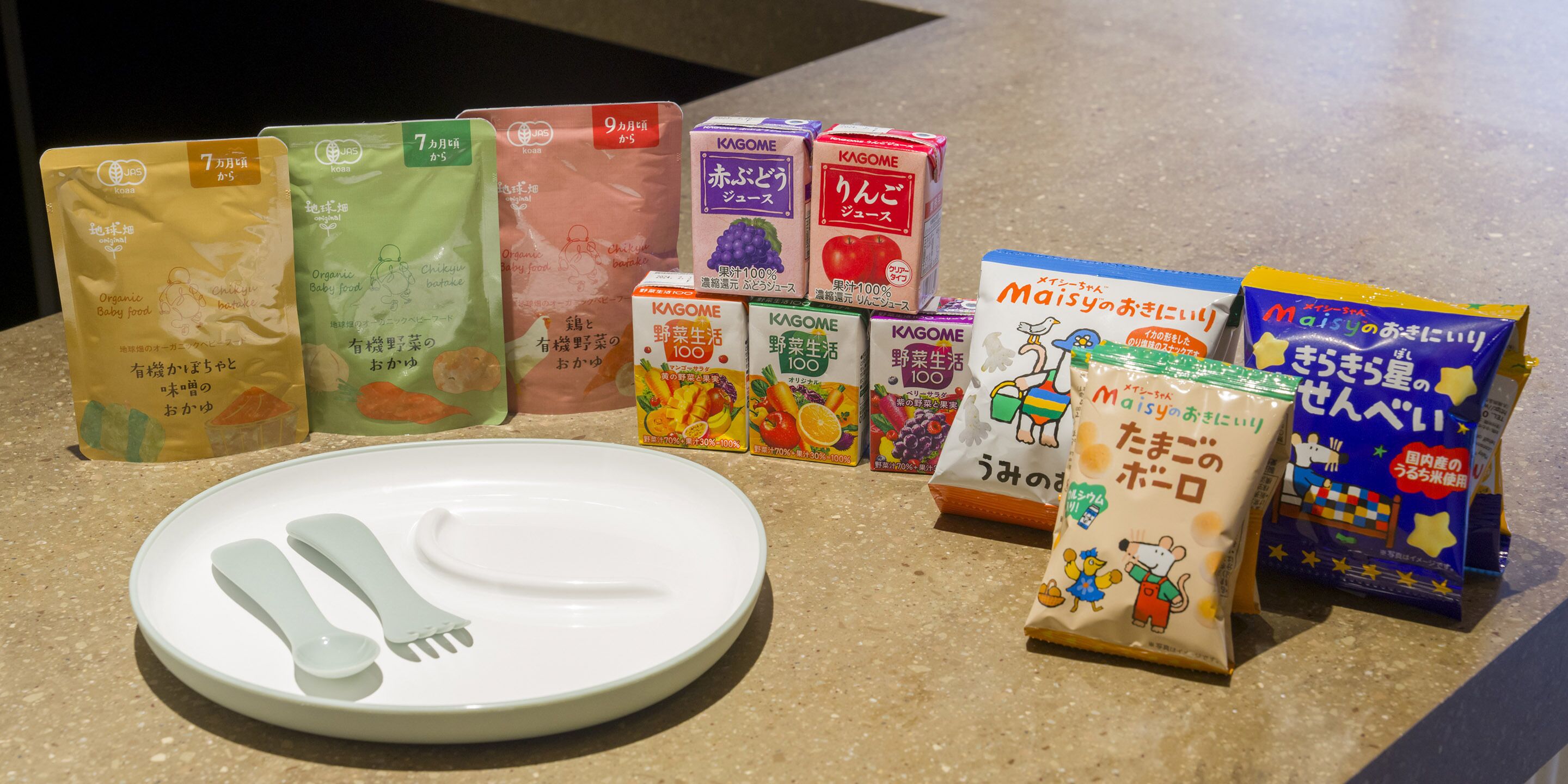 A variety of food products and a plate with utensils on a countertop.