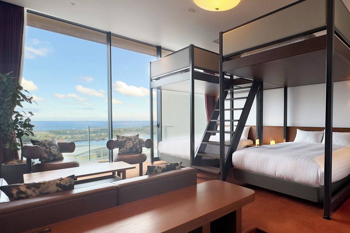 Una habitació d'hotel moderna amb un llit gran, una taula de treball i vistes a l'oceà.